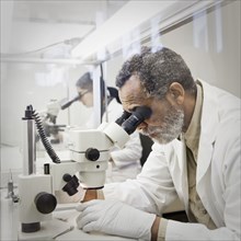 African American scientist using microscope in laboratory