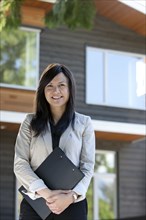 Mixed race real estate agent standing near house