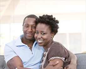 Smiling Black couple sitting on sofa together