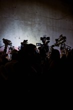 Silhouette of reporters and video cameras at press conference