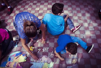 Hispanic family drawing with chalk on floor