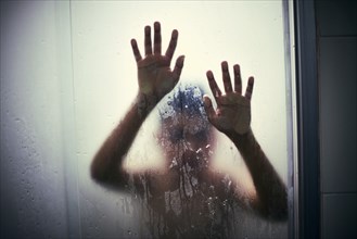 Hands of Hispanic boy leaning on shower door