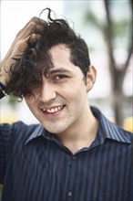 Smiling Hispanic man with hand in hair