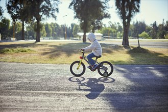 Hispanic boy riding bicycle with training wheels