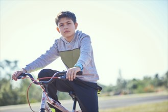 Serious Hispanic boy posing on bicycle
