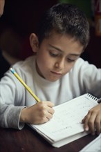 Hispanic boy practicing writing alphabet