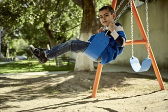 Hispanic boy on swing at park