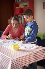 Hispanic mother and son painting stars at table