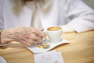 Hand of older Caucasian woman drinking coffee