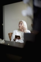 Older Caucasian woman applying makeup