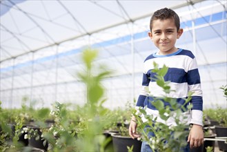 Portrait of Hispanic boy standing in greenhouse