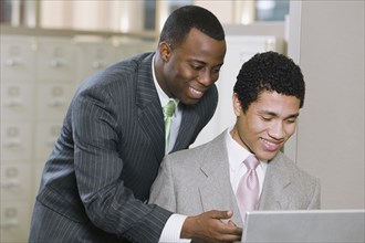 Multi-ethnic businessmen working on laptop in office