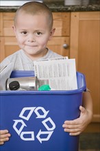 Hispanic boy holding recycling bin