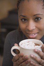 African woman holding cup of hot cocoa with marshmallows