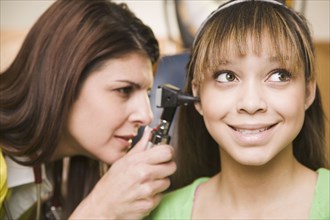 Mixed race doctor examining teenage girl's ears