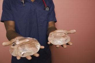 African doctor holding breast implants