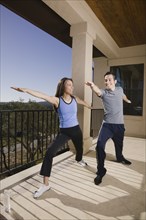 Hispanic couple doing yoga on balcony