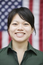Asian woman standing near American flag