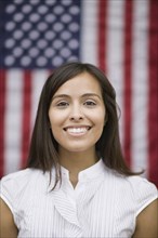 Hispanic woman standing near American flag