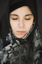Middle Eastern teenager in headscarf with eyes closed