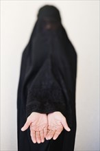 Middle Eastern woman in burka with hands outstretched