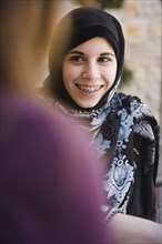 Middle Eastern teenager in headscarf talking to mother