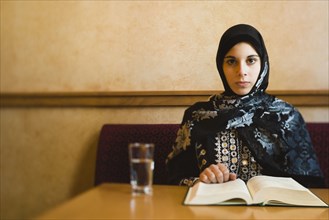 Middle Eastern teenager in headscarf reading book