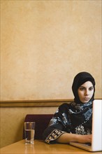 Middle Eastern teenager in headscarf using laptop