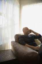 Mixed race man talking on cell phone in living room