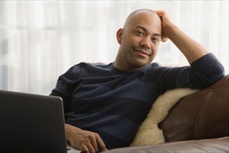 Mixed race man sitting in chair with laptop