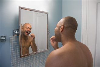 Mixed race man brushing teeth