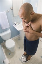 Mixed race man weighing himself on bathroom scale