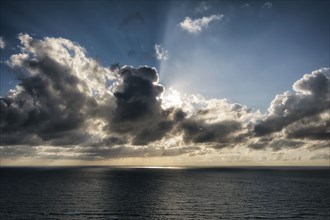 Sunbeams behind clouds over ocean