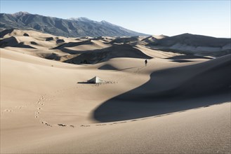 Footprints of camper walking near tent in sand dunes