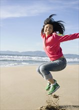 Asian woman jumping on beach