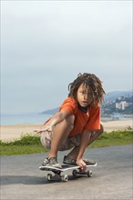 Mixed Race boy riding skateboard