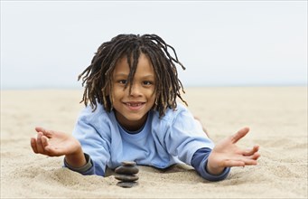 Mixed Race boy stacking stones on sand