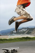 Mixed Race boy jumping over skateboard