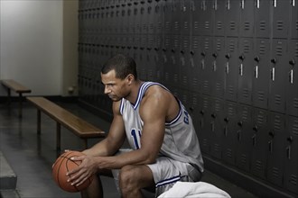 Mixed race basketball player sitting in locker room
