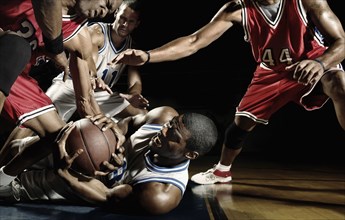 Multi-ethnic basketball players struggling for basketball