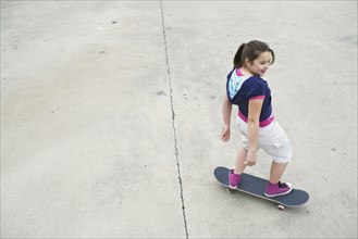 Mixed Race girl riding skateboard