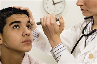 Female doctor checking young male patient's eye