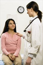 Female doctor with hand on young female patient's shoulder