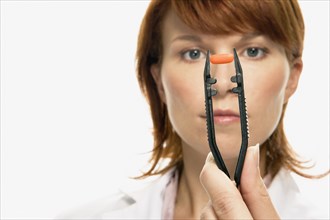 Woman holding pill in large tweezers