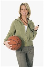 Studio shot of woman with whistle and basketball