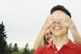 Woman covering boyfriend's eyes