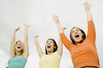 Three woman laughing with arms raised