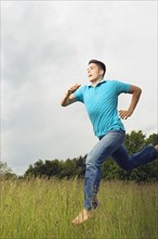 Young man running barefoot in meadow