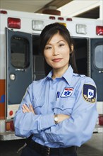 Portrait of Asian female paramedic in front of ambulance