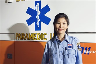 Portrait of Asian female paramedic next to ambulance